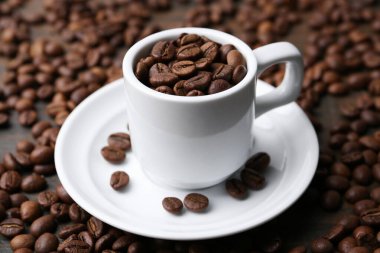 Aromatik kahve çekirdekleri, fincan ve çay tabağı masada, yakın plan.