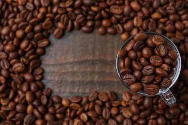 Aromatik kahve çekirdekleri ve cam bardaklar ahşap masada, düz yerde. Metin için boşluk