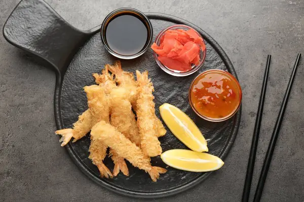 Lezzetli tempura karidesleri limon, zencefil ve sosla servis edilir gri desenli masa, düz uzanma