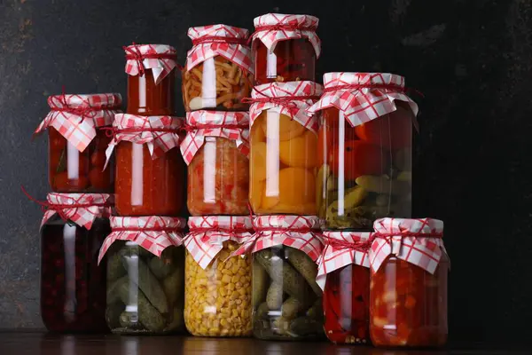 Ahşap masada farklı turşu ürünleri olan bir sürü kavanoz.