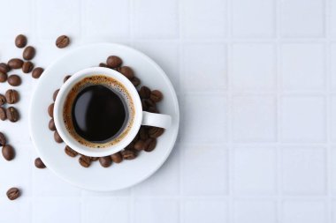 Aromatik kahve fincanda ve fasulye beyaz fayanslı masada, düz yerde. Metin için boşluk