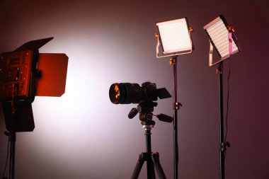 Renkli arka planda profesyonel ışıklandırma ekipmanı ve kamera