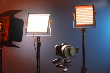 Renkli arka planda profesyonel ışıklandırma ekipmanı ve kamera