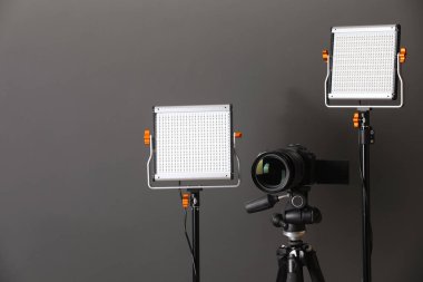 Profesyonel ışıklandırma ekipmanı ve gri arka planda kamera. Metin için boşluk