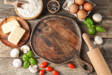 Pizza yapıyorum. Tahta masadaki farklı malzemeler, düz yatış. Metin için boşluk