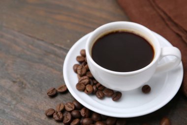 Aromatik kahve fincanda, fasulye ve çay tabağı ahşap masada, yakın plan. Metin için boşluk