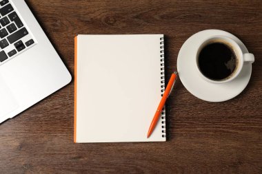 Defter, kalem, kahve ve dizüstü bilgisayar ahşap masada, düz yatıyordu.