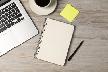 Defter, kalem, yapışkan not, sehpadaki kahve ve dizüstü bilgisayar, düz konum
