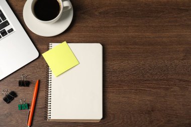 Not defteri, kalem, yapışkan not, cilt klipsleri, sehpadaki kahve ve dizüstü bilgisayar, düz yatak. Metin için boşluk