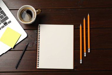 Defter, kalem, kalem, yapışkan not, sehpadaki kahve ve dizüstü bilgisayar, düz konum.