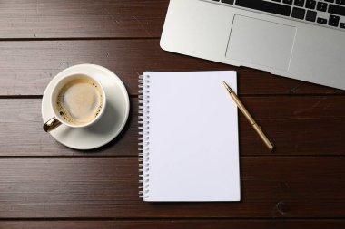 Defter, kalem, kahve ve dizüstü bilgisayar ahşap masada, düz yatıyordu.