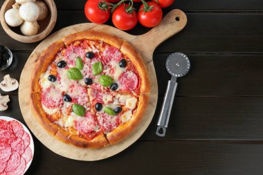 Lezzetli pizza, malzemeler ve siyah ahşap masa, düz yatak. Metin için boşluk