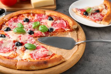 Gri masada servis edilen lezzetli pizza, yakın plan.