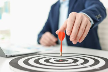 Dart oklu bir adam içeride çalışırken dart tahtasına nişan alıyor, yakın plan.