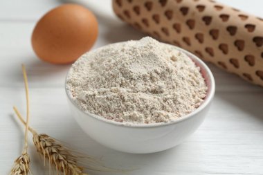 Kâsede un, merdane, yumurta ve çiviler beyaz ahşap masada, yakın plan.