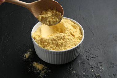 Siyah desenli masada kaseden kaşıkla mısır unu alıp, yakın plan.