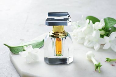 Parfüm ve yasemin çiçekleri açık gri masada, yakın plan