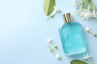 Parfüm ve yasemin çiçekleri açık mavi arka planda, düz yerde. Metin için boşluk