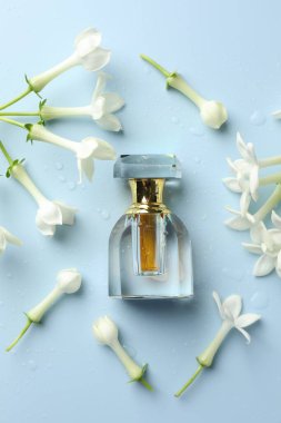 Parfüm ve yasemin çiçekleri açık mavi arka planda, düz yerde