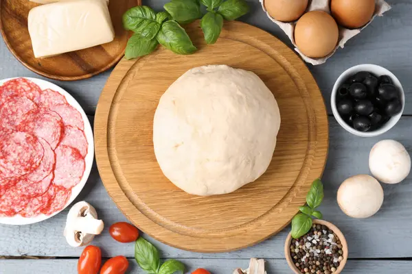 Pizza yapıyorum. Gri ahşap masadaki farklı malzemeler.