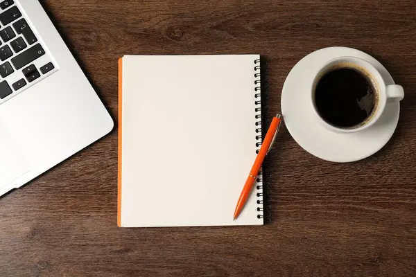 Defter, kalem, kahve ve dizüstü bilgisayar ahşap masada, düz yatıyordu.