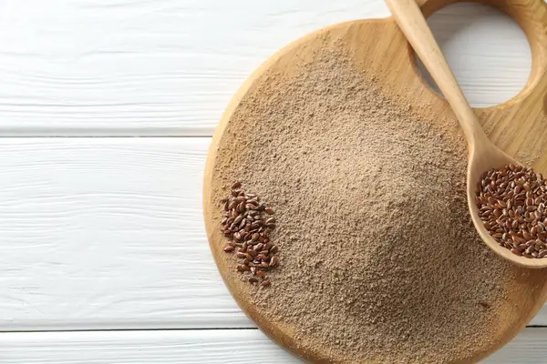 Keten tohumu unu ve kaşıkla beyaz ahşap masa, üst manzara. Metin için boşluk