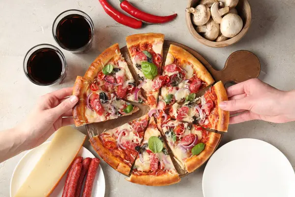 Işık masasında ince tütsülenmiş sosisle lezzetli bir pizza yiyen bir kadın.