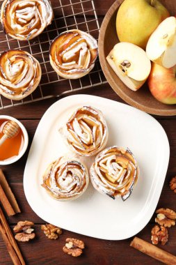 Ahşap masada servis edilen pudra şekerli lezzetli elma gülleri.