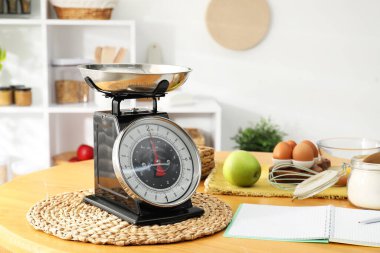 Retro mekanik mutfak ölçeği, ürünler ve ahşap masa üzerindeki kırtasiye.