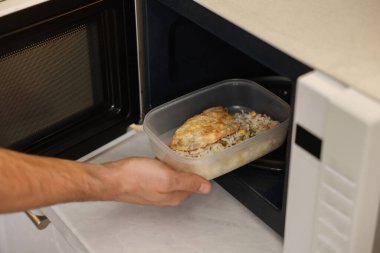 Yemek kabını mikrodalgaya koyan adam, yakın plan.