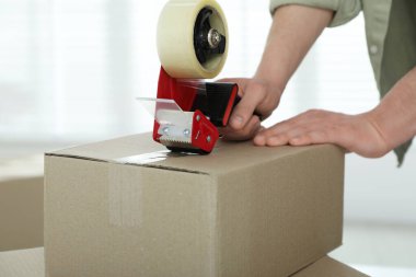 Karton kutuyu bantla kapatan adam içeride, yakın plan.