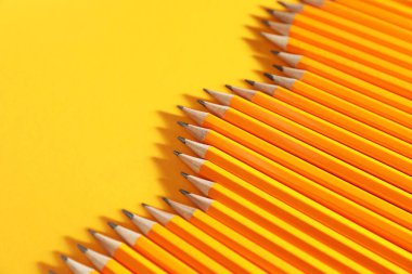 Many graphite pencils on yellow background, closeup. Space for text
