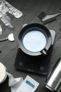 Beyazlatıcı toz ve kuaför aletleri siyah masada, düz yerde.