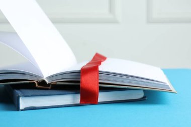 Kırmızı kurdele yer imine sahip bir kitap ve mavi masa üzerinde bir tane ışık arkaplan, yakın plan
