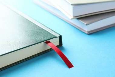 Kırmızı kurdele yer imi ve açık mavi arka planda renkli kitap, yakın plan