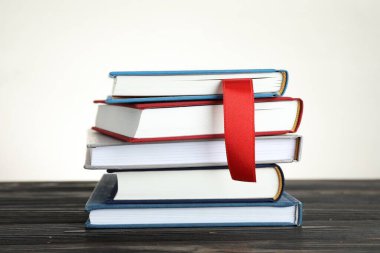 Kırmızı kurdele kitap ayracı ve renkli olanlar ahşap masa üzerinde ışık arkaplan, yakın plan