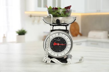 Mutfak terazileri yeşillik ve kapalı alandaki hafif mermer masada mezura.