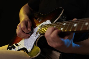 Siyah arka planda arabulucuyla gitar çalan adam, ele odaklan