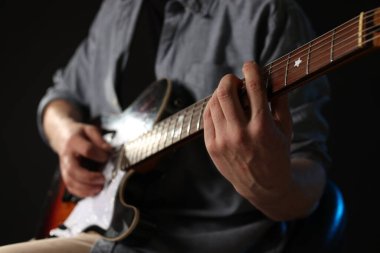 Siyah arka planda gitar çalan adam, ele odaklan.