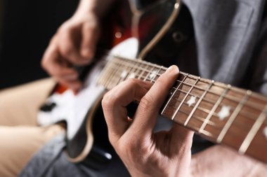 Siyah arka planda gitar çalan adam, ele odaklan.