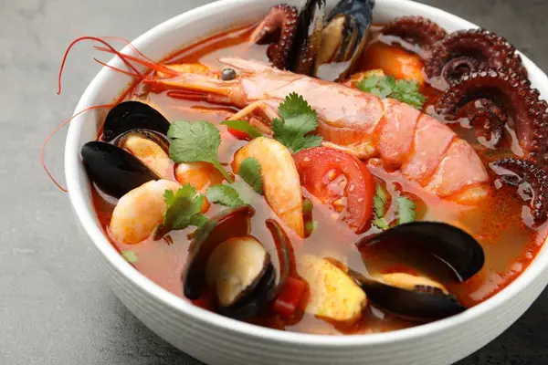 Gri desenli masada kasede lezzetli deniz ürünleri çorbası, yakın plan.