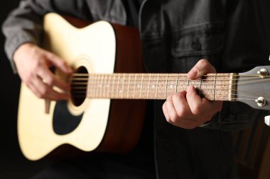 Siyah arkaplanda gitar çalan adam, yakın plan