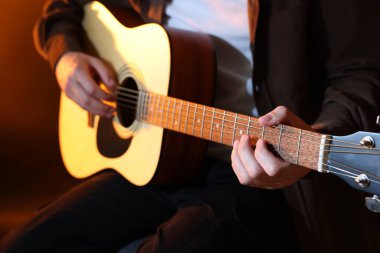 Kahverengi arka planda gitar çalan adam, yakın plan.