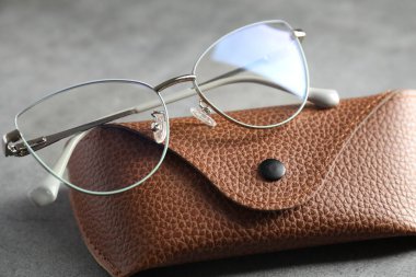 Gri masada şık gözlükleri olan bir çanta, yakın plan.