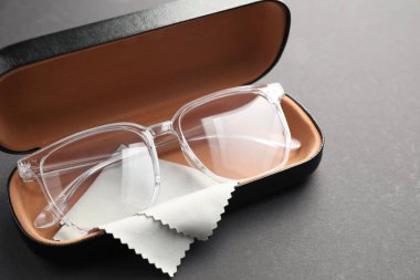 Gri arka planda şık gözlüklü ve temizlik bezli çanta, yakın plan.