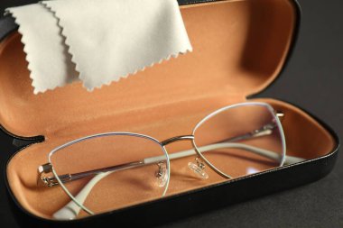 Gri arka planda şık gözlüklü ve temizlik bezli çanta, yakın plan.