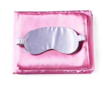 Beyaz arka planda ipek çarşaflar ve uyku maskesi, üst manzara.