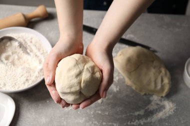 Açık gri masada hamur yoğuran kadın, yakın plan.