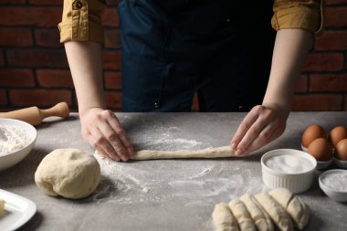 Açık gri masada simit yapan kadın, yakın plan.
