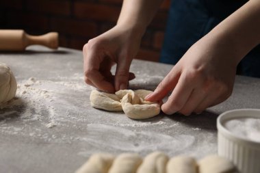 Açık gri masada simit yapan kadın, yakın plan.
